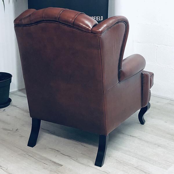 Bergère Chesterfield club de dos. Les pieds sont incurvés et la basane utilisée est marron sombre.