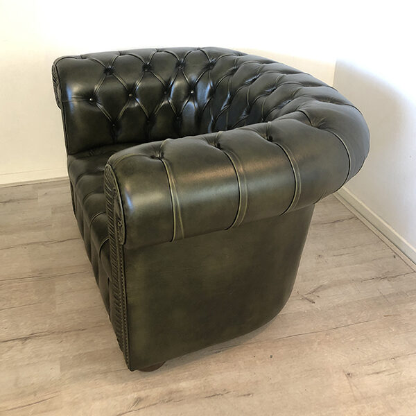 Fauteuil Chesterfield de profil recouvert d'un cuir vachette vert foncé. Capitons présents sur les acoudoirs, le dossier et l'assise.