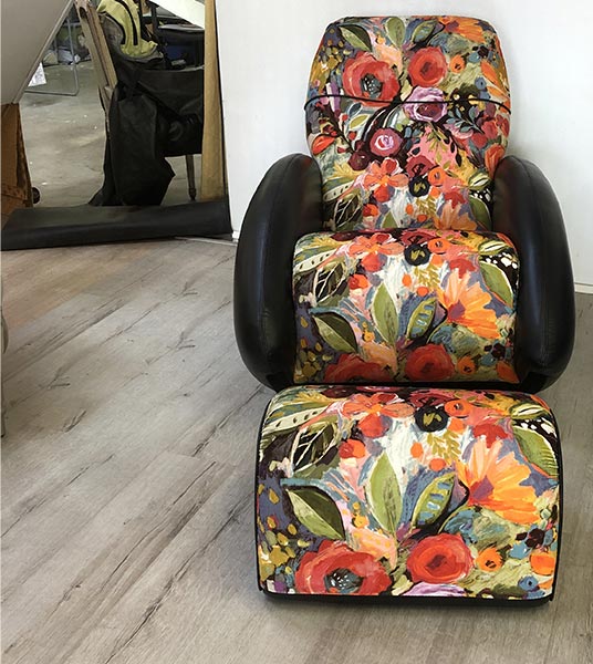 Fauteuil relax design avec un repose-pieds. Recouvrement en tissus à motifs colorés.