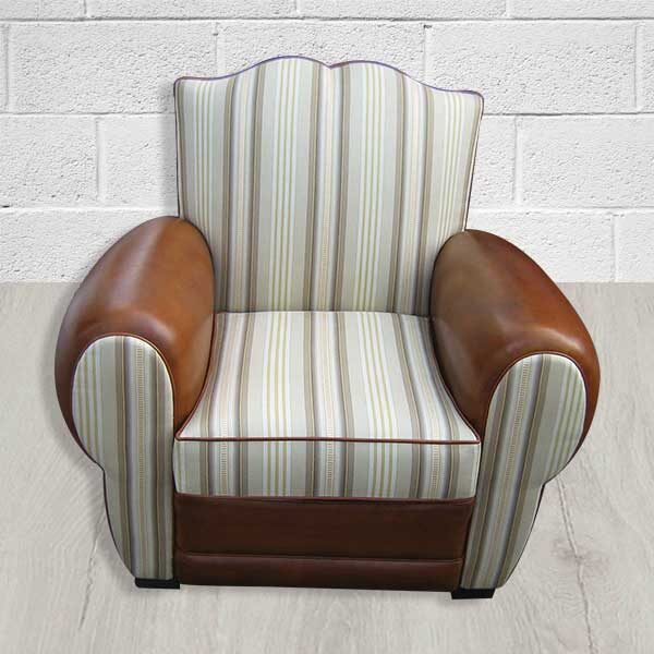 Fauteuil Club Moustache en cuir et en tissu. Le tissu est rayé blanc et gris. Le cuir est marron. Les deux s'accordent harmonieusement. Le fauteuil club mélange authenticité et confort